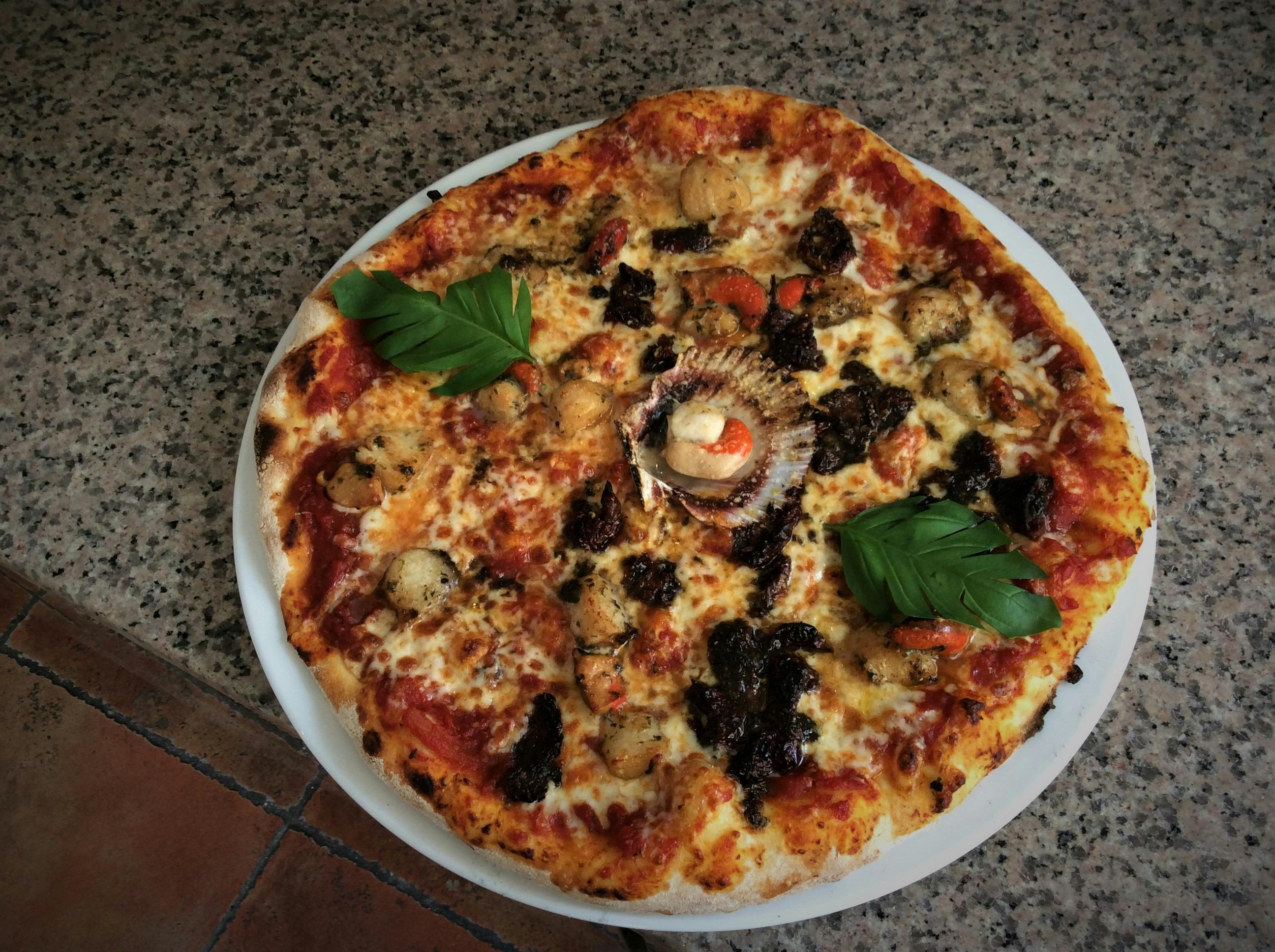 Photo d'une pizza au feu de bois dont la pâte est faite maison.